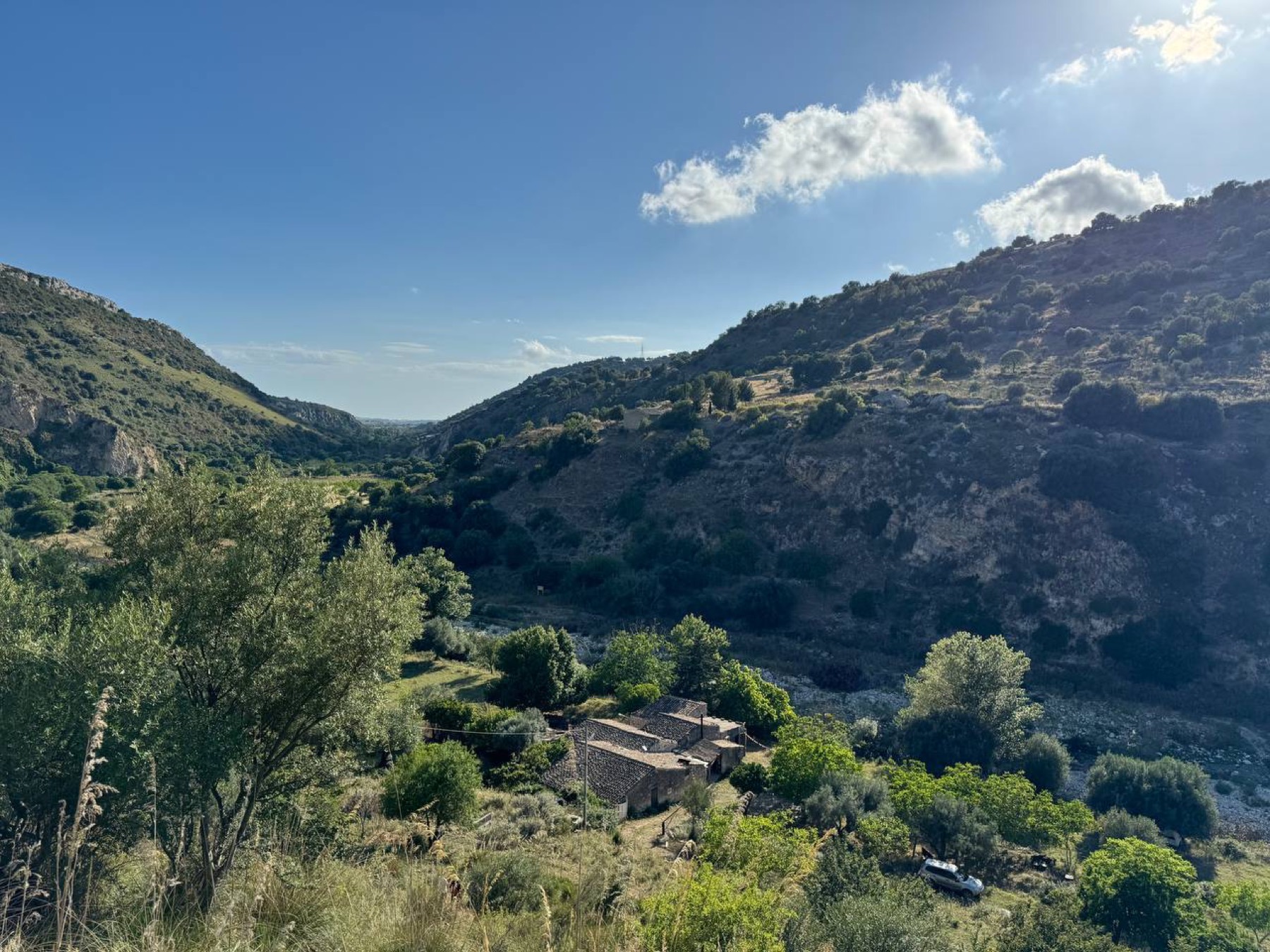 The il Nido valley: green hills, a stone house among the trees and blue sky